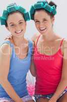 Girls in hair rollers sitting in bed and smiling