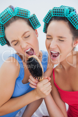 Friends in hair rollers holding hairbrush