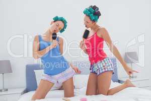 Girls in hair rollers singing with hairbrush