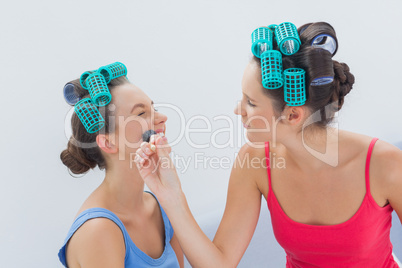 Friends in hair rollers having fun with makeup