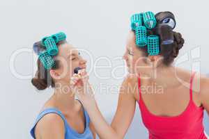 Friends in hair rollers having fun with makeup