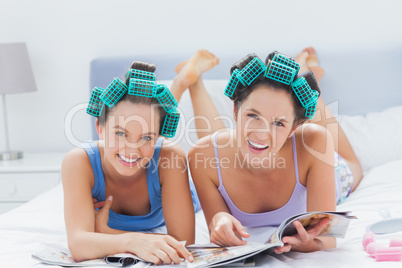 Girls in hair rollers holding magazines