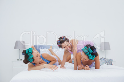 Girls in hair rollers having fun in bed