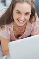 Woman lying on sofa with laptop