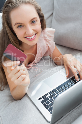 Woman shopping online with her laptop smiling at camera