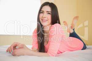 Smiling girl looking at camera lying on her bed