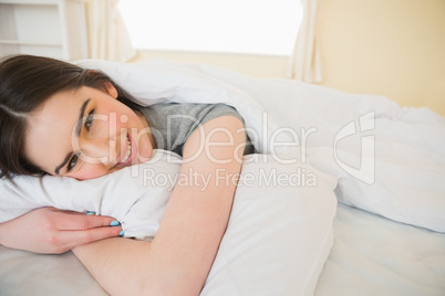 Happy brunette relaxing in her bed