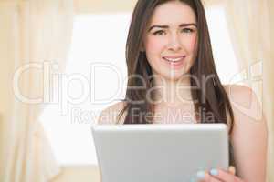 Pretty girl looking at camera and using a tablet pc sitting on h