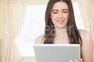 Content girl using a tablet pc sitting on her bed