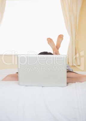 Girl lying on a bed behind a laptop