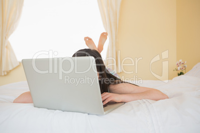 Girl on a bed hiding behind a laptop