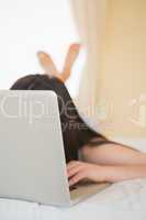 Laptop covering girls face on bed