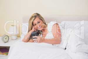 Happy woman texting on her mobile phone and lying on her bed
