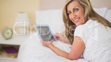 Happy woman using a tablet pc lying on her bed