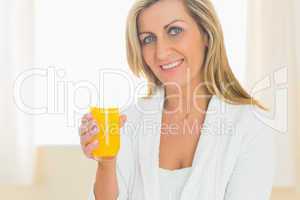 Content woman looking at camera enjoying a glass of orange juice