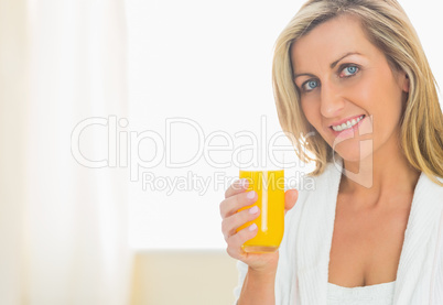 Satisfied woman looking at camera enjoying a glass of orange jui