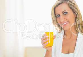 Satisfied woman looking at camera enjoying a glass of orange jui