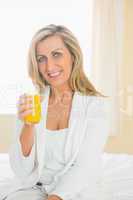 Joyful woman looking at camera enjoying a glass of orange juice