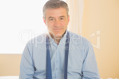 Content man looking at camera sitting on a bed