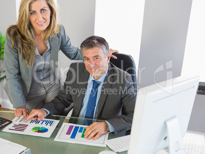 Businesspeople posing at camera studying figures