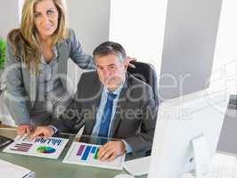 Businesspeople posing at camera studying figures