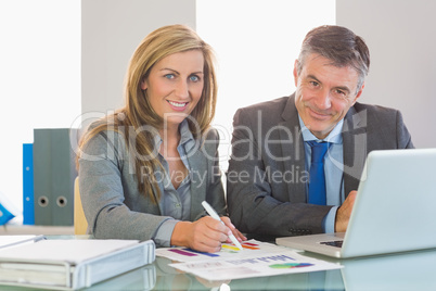 Two concentrated business people smiling at camera trying to und