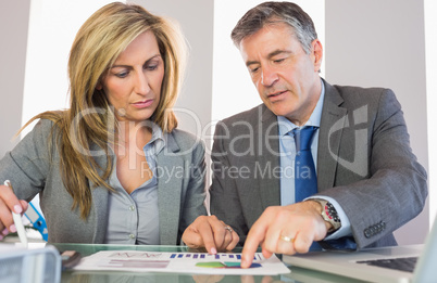 Two frowning business people pointing at a graphic