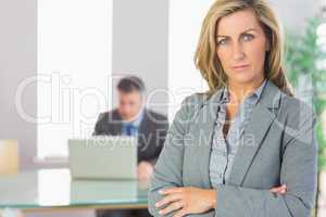 Unsmiling businesswoman looking at camera crossed arms with a bu