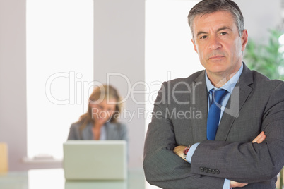 Unsmiling businessman looking at camera crossed arms with a busi
