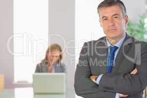 Unsmiling businessman looking at camera crossed arms with a busi