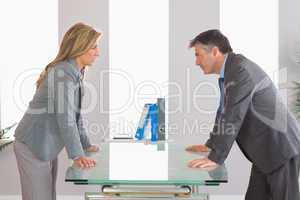 Two irritated businesspeople arguing on each side of a desk