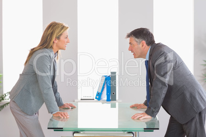 Two angry businesspeople arguing on each side of a desk