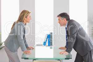 Two angry businesspeople arguing on each side of a desk