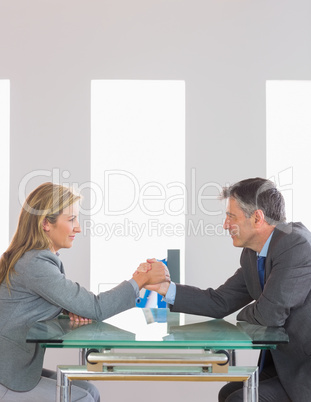 Two content businesspeople having an arm wrestling sitting aroun