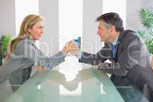 Two upset businesspeople having an arm wrestling sitting around