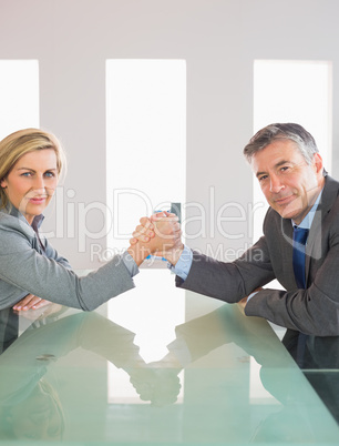 Two smiling businesspeople having a showdown sitting around a ta