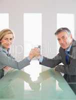 Two smiling businesspeople having a showdown sitting around a ta