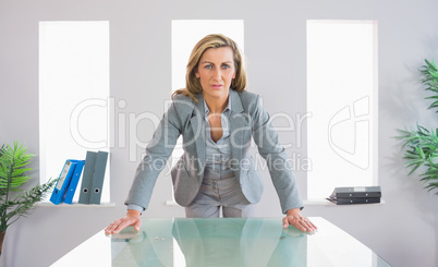 Serious businesswoman standing in front of a desk