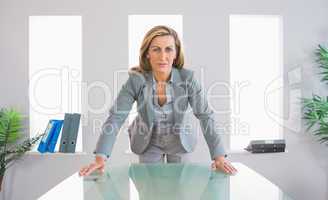 Serious businesswoman standing in front of a desk