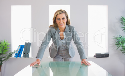 Pleased businesswoman standing in front of a desk