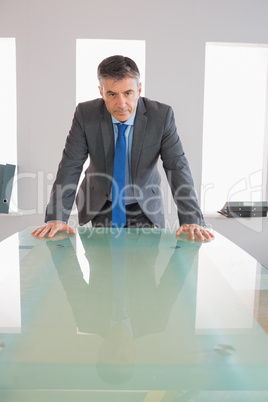Serious businessman standing in front of a desk