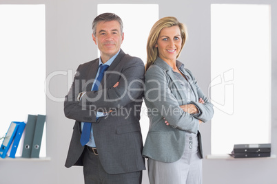 Two smiling businesspeople looking at camera standing back to ba