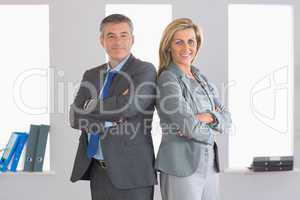 Two smiling businesspeople looking at camera standing back to ba