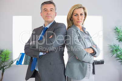 Two serious businesspeople looking at camera standing back to ba