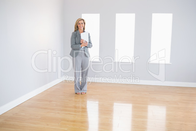 Joyful realtor standing in a room holding documents