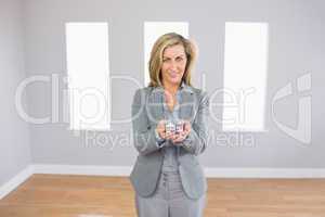 Cheerful realtor standing in a room presenting a mini model hous