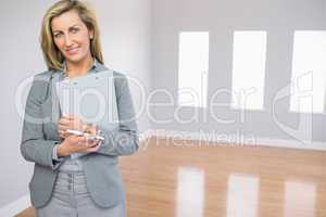 Satisfied realtor standing in a room holding documents