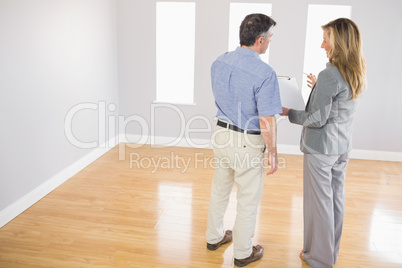Blonde realtor showing a room and some documents to a potential