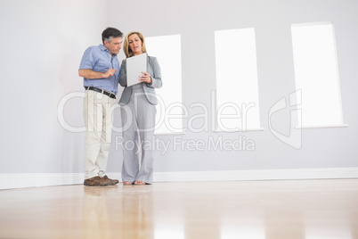 Concentrated blonde realtor showing a room and some documents to