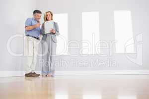 Cheerful blonde realtor showing a room and some documents to a p